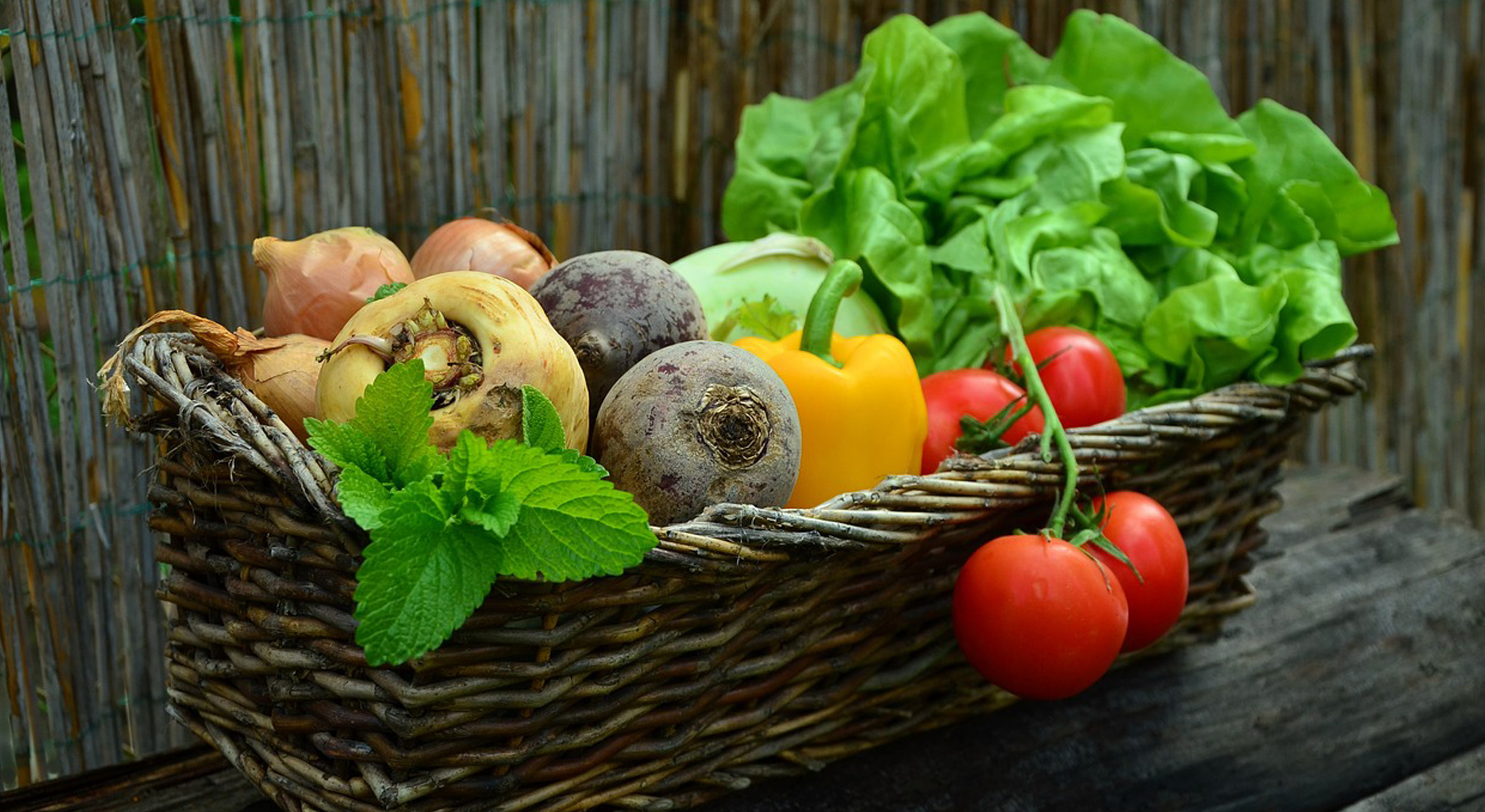 An image displaying a woven basket filled with an array of colorful, fresh fruits and vegetables. The assortment includes vibrant red tomatoes, leafy greens, crisp bell peppers, deep purple eggplants, bright oranges, yellow squash, and various other seasonal produce. The arrangement symbolizes a diverse selection of nutritious foods rich in antioxidants and anti-inflammatory properties. The vibrant colors and variety of fruits and vegetables signify a wholesome and balanced approach to an anti-inflammatory dietary protocol, promoting overall health and wellness.