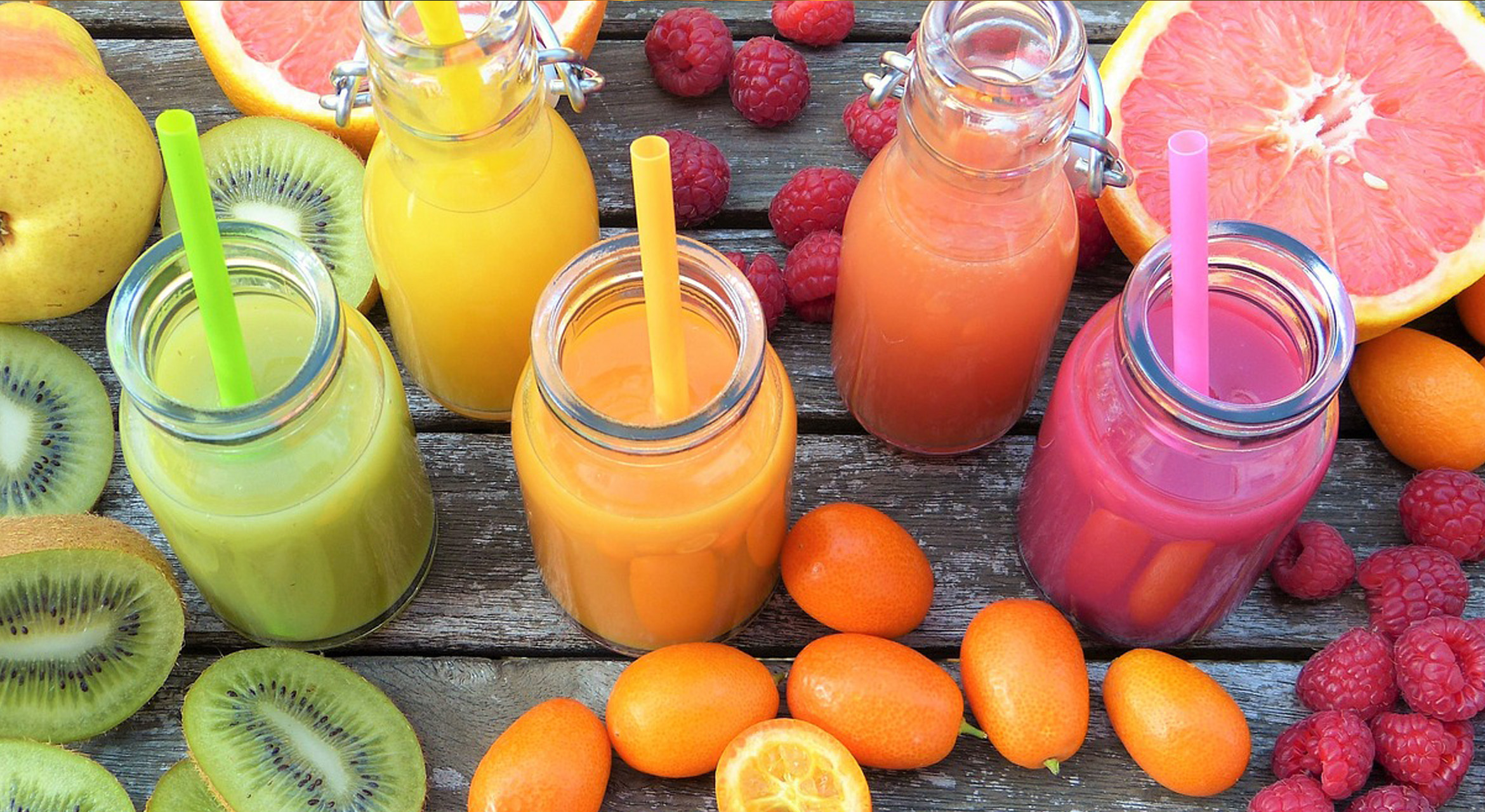 Image showcasing a colorful array of fresh fruits and vegetables arranged around a juicer, symbolizing juicing for detox for beginners.